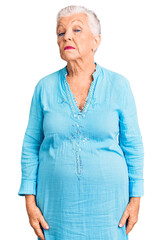 Senior beautiful woman with blue eyes and grey hair wearing summer dress relaxed with serious expression on face. simple and natural looking at the camera.