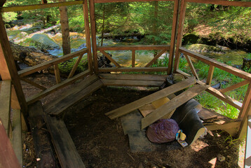 Garbage thrown by people into a gazebo in nature near a beautiful mountain river in the middle of a...