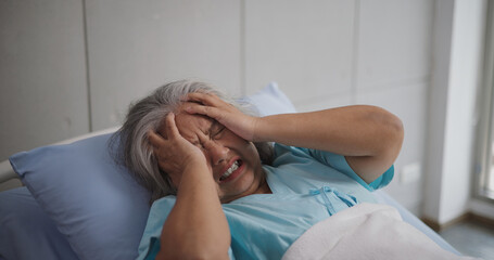 Portrait of Elderly female patient who was hospitalized was holding her head on the hospital bed in...