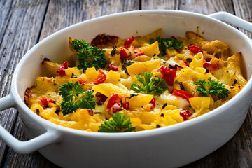 Noodle casserole with mozzarella cheese and vegetables on wooden table
