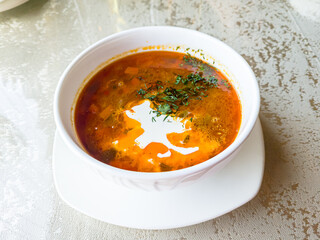 Thick tomato soup with meat in a plate on the table in a restaurant