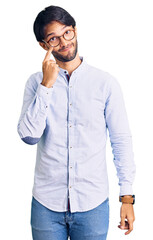 Handsome hispanic man wearing business shirt and glasses pointing to the eye watching you gesture, suspicious expression