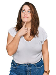 Young plus size woman wearing casual white t shirt thinking concentrated about doubt with finger on chin and looking up wondering