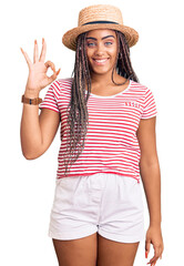 Young african american woman with braids wearing summer hat smiling positive doing ok sign with...