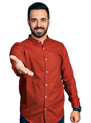 Young hispanic man with beard wearing casual shirt smiling cheerful offering palm hand giving assistance and acceptance.