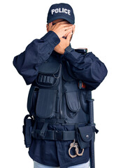 Young hispanic man wearing police uniform covering eyes and mouth with hands, surprised and shocked. hiding emotion