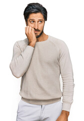 Fototapeta na wymiar Young hispanic man wearing casual clothes looking stressed and nervous with hands on mouth biting nails. anxiety problem.