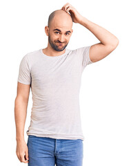 Fototapeta premium Young handsome man wearing casual t shirt confuse and wonder about question. uncertain with doubt, thinking with hand on head. pensive concept.