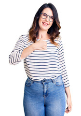 Fototapeta premium Beautiful young brunette woman wearing casual clothes and glasses doing happy thumbs up gesture with hand. approving expression looking at the camera showing success.
