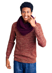 Young african american man wearing casual winter sweater and scarf pointing with hand finger to...