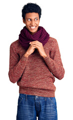 Young african american man wearing casual winter sweater and scarf laughing nervous and excited...