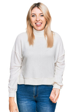 Young caucasian woman wearing casual winter sweater sticking tongue out happy with funny expression. emotion concept.