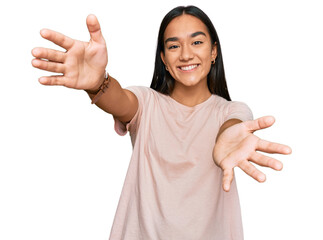 Young asian woman wearing casual clothes looking at the camera smiling with open arms for hug. cheerful expression embracing happiness. - obrazy, fototapety, plakaty
