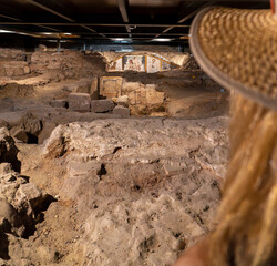 Blond woman with straw hat looking at the ruins and religious wall paintings and frescoes of the...