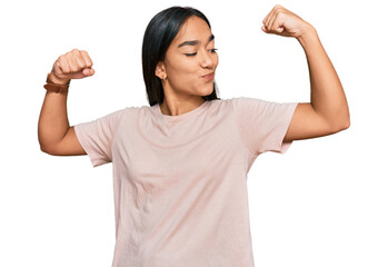 Young asian woman wearing casual clothes showing arms muscles smiling proud. fitness concept.