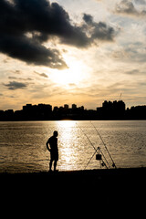 Silhouette of a man, fishing at Han River with the sunsets and view of Seoul city in the background