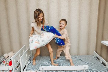 Naughty children A little boy and a girl had a pillow fight on the bed in the bedroom. brother and...