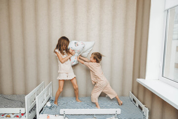 Naughty children A little boy and a girl had a pillow fight on the bed in the bedroom. brother and sister playing with pillows on the bed - obrazy, fototapety, plakaty