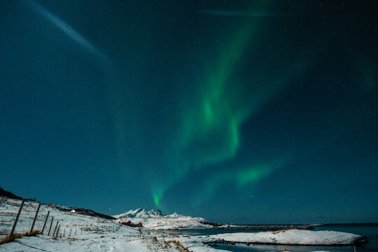 Bright Green Colours of the Northern Light, Aurora Borealis illuminate the Night Sky over the beach at Mjelle, in Arctic Norway.