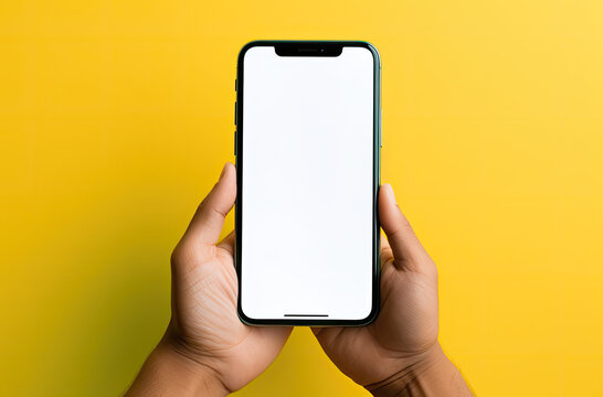 hands holding a blank smartphone in front of a yellow background