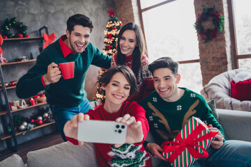 Photo of group best friends sitting sofa hold smart phone make selfie drink cacao new year giftbox...
