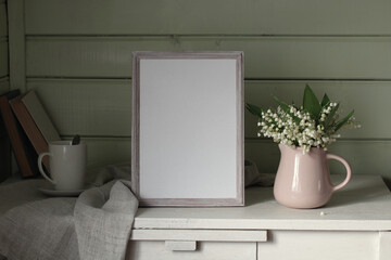 an empty frame and lilies of the valley. Cottage interior. background, copy space. summer stage creator.