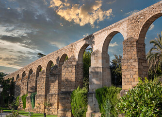 Vista de los pilares y arcos del histórico acueducto romano en la villa de Plasencia, España, con cielo editado