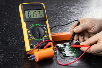 An electrician takes readings from a microcircuit using a multimeter. Measuring instruments. Copy...