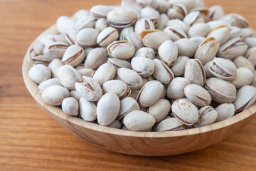 Pistachios in a wooden bowl. Wooden background. Healthy food