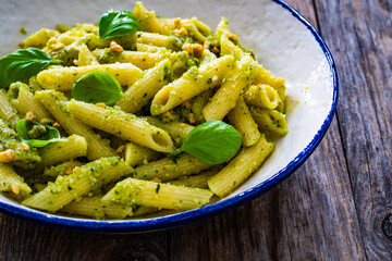 Penne with basil pesto sauce on wooden table