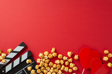 Romantic Movie Night: Overhead shot of a clapperboard, popcorn, and heart-shaped decor on a red...