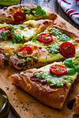 Pinsa Romana with mozzarella cheese and basil pesto on wooden table
