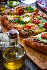 Pinsa Romana with mozzarella cheese and basil pesto on wooden table
