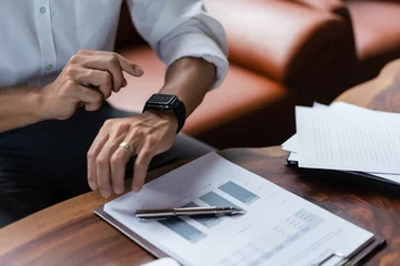Foto op Canvas Hands of businessman checking time on smartwatch while working about financial document of business © Pichsakul