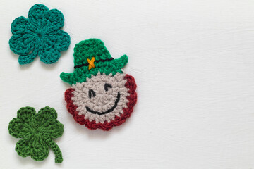 Handmade crochet St Patrick's day leprechaun and clover shamrock close up on a white background....