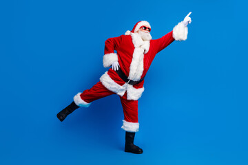 Fototapeta na wymiar Full length photo of mature pensioner man point empty space dancing wear trendy santa claus costume coat isolated on blue color background