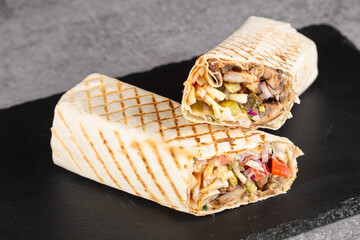 Burrito wraps with chicken and vegetables on a cutting board, against a background