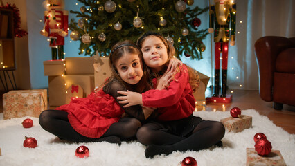 Young ladies playing and hugging under the Christmas tree 