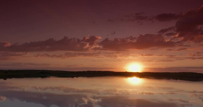Sunrise on cloudy morning over calm lake in calm weather