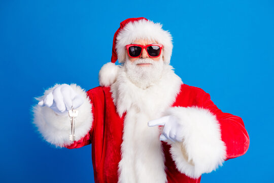 Photo portrait of pensioner senior man hold point door key house wear trendy santa claus costume coat isolated on blue color background