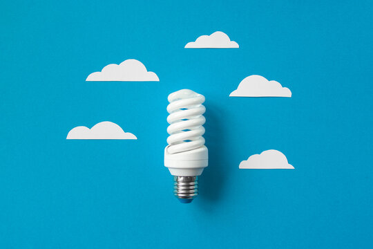 Light bulb with white cut out clouds on blue background. Idea concept. Energy and electricity. alternative energy sources. Innovation and thinking out the box symbols. Creativity and inspiration