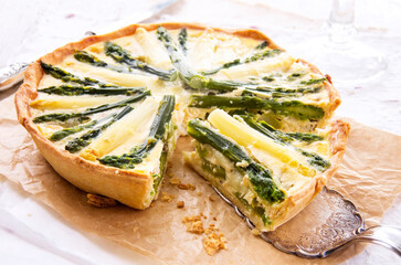 Traditional French vegetable tarte with green and white asparagus served as close-up on brown...