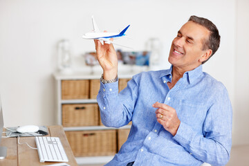 Mature man, freedom and toy plane for travel, vacation and holiday planning with a smile at home. Happy, airplane model and retirement of a male person with thinking from trip and air traveling