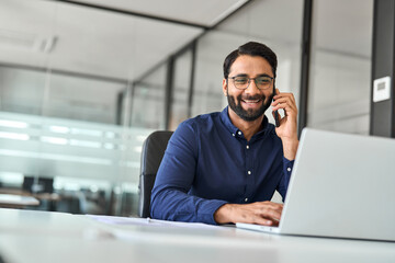 Smiling business man expert making call on mobile cellphone, consulting client at work. Happy...