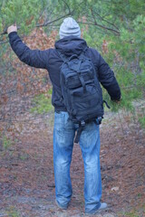 one brack army backpack on the back of a man in a gray hat and jacket on an autumn street