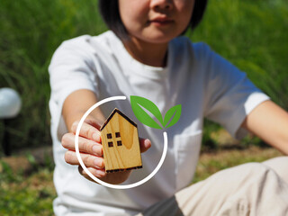 Net Zero concept, young woman holding a wooden house Reduce greenhouse gas emissions...