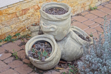 one gray concrete pot with soil stands on a brown sidewalk near a wall on the street