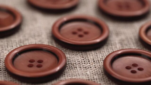 kit of large brown buttons on a fabric background made of burlap. closeup rotation. accessories for sewing and needlework. sewing supplies for the tailor's work. sewing buttons.