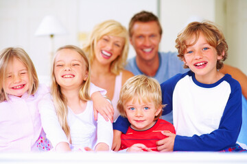 Smile, portrait and parents with children on bed for bonding, relaxing and spending time together. Happy, love and young mother and father resting with kids from Australia in bedroom at family home.