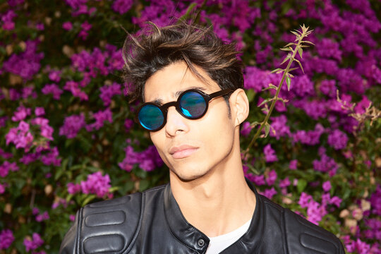 Portrait of a handsome serious latin man wearing sunglasses and leather jacket looking at camera